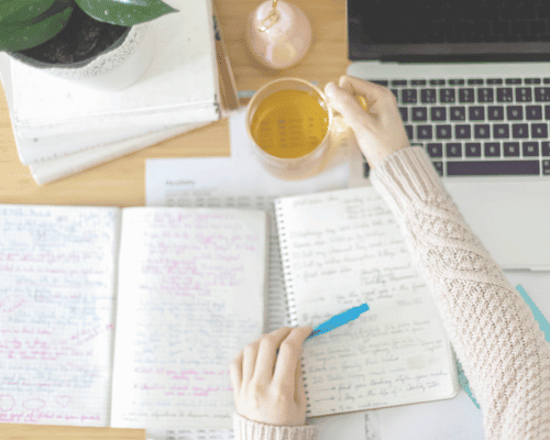 Desk setup with a notebook titled Urgent vs Important and a cup of tea.